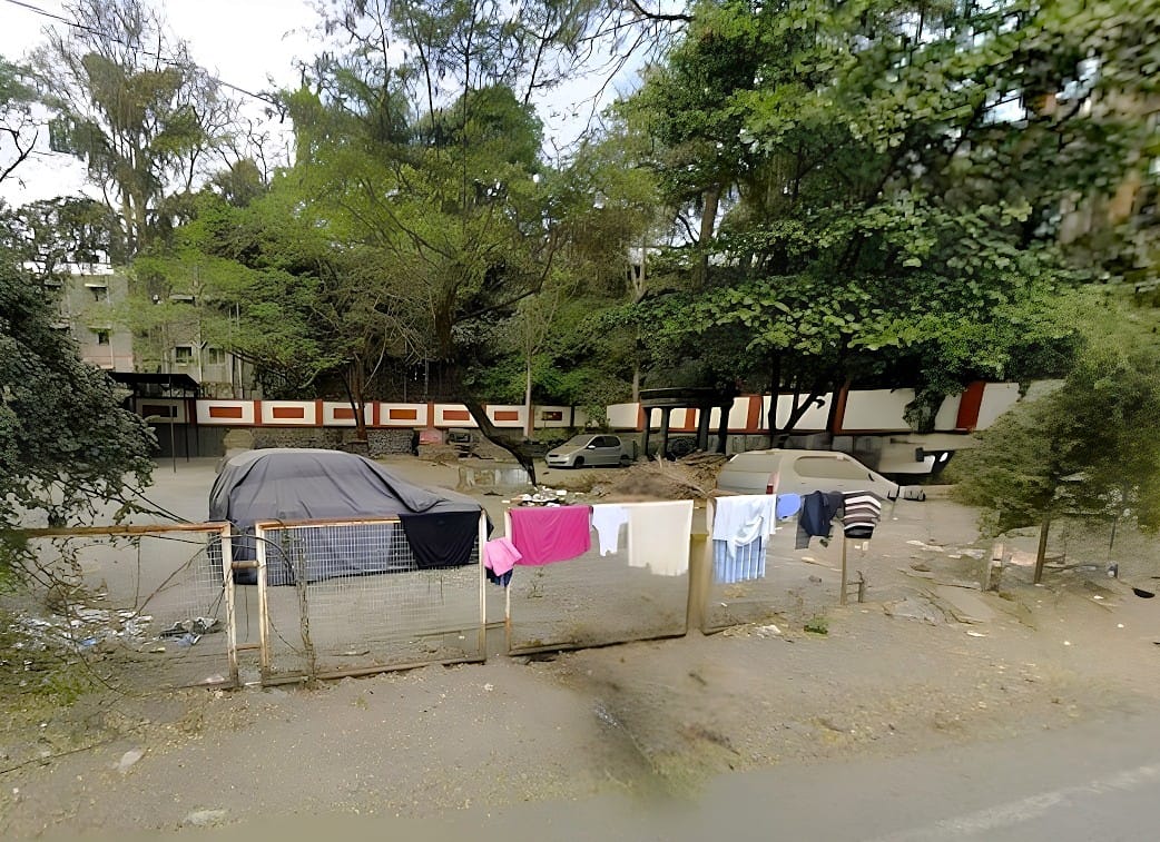 The walled boundary of the St. Paul's Church Road Cemetery seen from Church Road, Pune Camp, with washing hung on the roadside fence